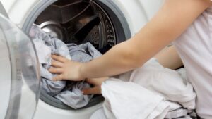 persona metiendo ropa lavarropa